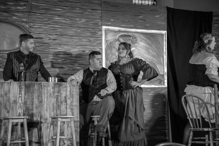 Actors performing a black-and-white saloon scene in a western stage production